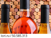 Closeup of three wine bottles two chardonnay and one red in front of a mass of out of focus corks. Стоковое фото, агентство Ingram Publishing / Фотобанк Лори