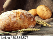 freshly baked loaf of homemade bread with wheat spikelets, lies on a wooden table. rustic style. closeup. Стоковое фото, агентство Ingram Publishing / Фотобанк Лори