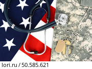 Military fatigues and dog tags on an American Flag with a stethoscope to illustrate health care in the armed services. Horizontal format, fills the frame. Стоковое фото, агентство Ingram Publishing / Фотобанк Лори