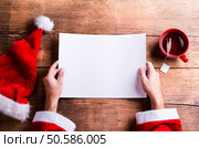 Santa Claus holding an empty wish list in his hands. Santa Claus and wishlist. Стоковое фото, агентство Ingram Publishing / Фотобанк Лори