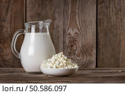 Natural rustic whole milk in a glass jug and cottage cheese on the old wooden background closeup. Natural rustic whole milk. Стоковое фото, агентство Ingram Publishing / Фотобанк Лори