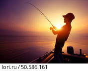Young man fishing on wide river from the boat at sunset. Стоковое фото, агентство Ingram Publishing / Фотобанк Лори