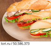 three sandwiches with savoury fillings on a cutting board. submarine sandwiches on a cutting board. Стоковое фото, агентство Ingram Publishing / Фотобанк Лори