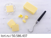 Butter on white wood table with slices, block, crystal butter dish and butter curler utensil. . Стоковое фото, агентство Ingram Publishing / Фотобанк Лори