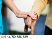 Doctor holding a senior patiens ’s hand on a walking stick - special medical care concept for Alzheimer ’s syndrome. Стоковое фото, агентство Ingram Publishing / Фотобанк Лори