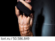 Muscular and sexy body of young man stripping. Стоковое фото, агентство Ingram Publishing / Фотобанк Лори