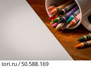 Crayons in a white mug on a wooden table next to blank white paper. Стоковое фото, агентство Ingram Publishing / Фотобанк Лори