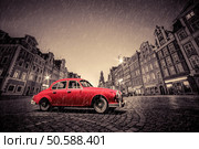 Retro red car on cobblestone historic old town in rain. The market square at night. Wroclaw, Poland.. Retro red car on cobblestone historic old town in rain. Wroclaw, Poland. Стоковое фото, агентство Ingram Publishing / Фотобанк Лори