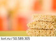 Noodles square blocks stacked on top of each other, green surface and blurry background.. Noodles square blocks stacked on top of each other, green surface and blurry background. Стоковое фото, агентство Ingram Publishing / Фотобанк Лори