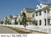 Long row of suburban townhouses with a white picket fence in front. . Стоковое фото, агентство Ingram Publishing / Фотобанк Лори