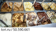 Display window in a store or ice cream parlour of assorted ice cream flavours for sale as summer takeaways displayed in metal trays with scoops. Display window of assorted ice cream flavours. Стоковое фото, агентство Ingram Publishing / Фотобанк Лори