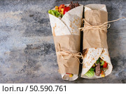Mexican style dinner. Two papered tortillas burrito with beef and vegetables over old textured tin background. Flat lay with copy space. Tortillas and nachos. Стоковое фото, агентство Ingram Publishing / Фотобанк Лори