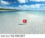 Aerial view of sporty slim woman with swimming ring, sandy beach, blue sea during low tide at sunny summer day in Zanzibar island. Top view of beautiful girl, sandbank, ocean, sky with clouds, palms. Стоковое фото, агентство Ingram Publishing / Фотобанк Лори
