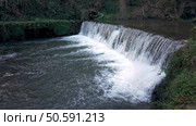 A man-made weir creates a powerful cascade on the river near Cascata do Outeiro. The rushing water and surrounding greenery create a dynamic scene in Oliveira de Azemeis. Стоковое фото, агентство Ingram Publishing / Фотобанк Лори