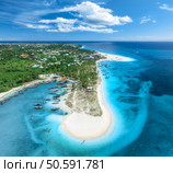 Aerial view of the boats on tropical sea coast with white sandy beach on summer sunny day. Travel in Kendwa, Zanzibar island. Landscape with boats, clear blue water, sky, clouds, palms. Top drone view. Стоковое фото, агентство Ingram Publishing / Фотобанк Лори