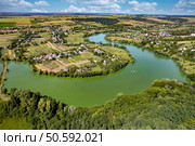 Aerial view of picturesque village surrounded by lush green fields and winding river creating serene bays. Charming rural houses blending with nature.. Aerial view of village surrounded by green fields and winding river. Стоковое фото, агентство Ingram Publishing / Фотобанк Лори