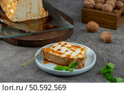 A delectable slice of molotof, a traditional caramelized egg white pudding drizzled with sweet syrup and garnished with fresh mint leaves, sits on a light blue plate. Стоковое фото, агентство Ingram Publishing / Фотобанк Лори