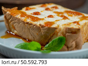 A tempting close-up showcases a slice of molotof, a classic caramelized egg white pudding, generously coated with a glistening caramel syrup and adorned with fresh mint leaves on a delicate blue plate. Стоковое фото, агентство Ingram Publishing / Фотобанк Лори