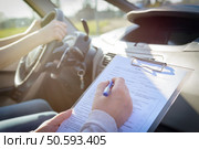 Examiner filling in driver’s license road test form. Стоковое фото, агентство Ingram Publishing / Фотобанк Лори