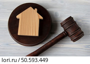 Judge’s hammer lies on a light wooden table against the background of the house. Стоковое фото, агентство Ingram Publishing / Фотобанк Лори