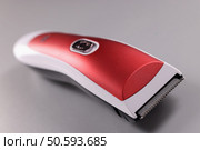 Red hair clipper on a gray background. Choosing a quality hair machine concept. Red hair clipper on a gray background. Стоковое фото, агентство Ingram Publishing / Фотобанк Лори