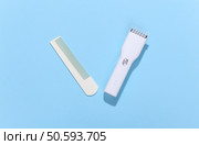 Wireless hair clipper and comb on blue bright background. Top view. Стоковое фото, агентство Ingram Publishing / Фотобанк Лори