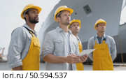 Professional dockworkers wearing safety helmets and overalls collaborating during maritime operations. Analyzing cargo logistics with shared clipboard. Стоковое AI-видео, аниматор Юрий Поздников / Фотобанк Лори