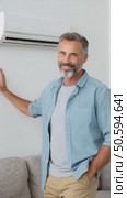 Mature man smiling and leaning against wall with air conditioner. Стоковое AI-видео, аниматор Юрий Поздников / Фотобанк Лори