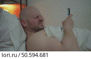 An adult man lies in bed in an uncomfortable hunched position at night, uses a smartphone, then writhes in pain and touches his neck. Spine problems due to incorrect posture when using modern gadgets. Стоковое видео, видеограф Денис Кебедов / Фотобанк Лори