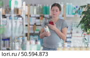 Pregnant woman scans shampoo on her mobile phone with interest and reads the instructions before buying. Стоковое видео, видеограф Яков Филимонов / Фотобанк Лори