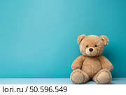 Cute teddy bear sitting on blue background with copy space. Стоковое AI-изображение, AI-художник Иван Рябоконь / Фотобанк Лори