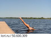 Fit woman diving headfirst from pier into lake. Healthy body, strong motion, natural summer activity. Стоковое фото, фотограф Скоробогатова Е. / Фотобанк Лори