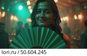 A woman with a green fan smiling in a dimly lit venue, fairy lights creating bokeh effects in background, music laser show on background. Стоковое AI-видео, аниматор Sergey Grishin / Фотобанк Лори