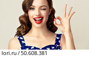 Pin-up retro girl with curly hair  winking, smiling and showing OK sign . Presenting your product. Expressive facial expressions. Стоковое фото, фотограф Sofia Zhuravetc / Фотобанк Лори