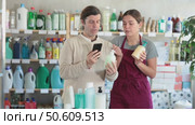 Girl seller help man visitor scan QR code, get information about liquid hand soap in mobile app. Стоковое видео, видеограф Яков Филимонов / Фотобанк Лори