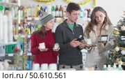 Cheerful family, parents and teenage daughter, shopping for cosmetics and perfumes in Christmas decorated store, comparing beauty products and discussing choices. Стоковое видео, видеограф Яков Филимонов / Фотобанк Лори