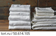 Neatly folded white t-shirts stacked on a wooden surface. Many folded white basic cotton linen presented in rustic interior. Minimalist clothing organization and clean laundry concept. Стоковое AI-видео, аниматор Sergey Grishin / Фотобанк Лори
