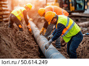 Workers wearing high-visibility vests and hard hats methodically position a utility pipe into a trench. The construction site scene highlights teamwork and safety in infrastructure projects. Стоковое AI-изображение, AI-художник Nart / Фотобанк Лори