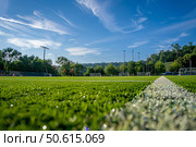 Lush green artificial turf soccer field on sunny day. Стоковое AI-изображение, AI-художник Иван Рябоконь / Фотобанк Лори