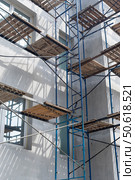 Фасад здания с установленными строительными лесами. Building under construction in scaffolding around the house for cement plastering work on the high outer wall. Стоковое фото, фотограф Татьяна Д / Фотобанк Лори