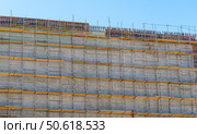 Фасад здания с установленными строительными лесами. Building under construction in scaffolding around the house for cement plastering work on the high outer wall. Стоковое фото, фотограф Татьяна Д / Фотобанк Лори