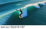 Aerial drone view of a female surfer riding a large, perfect turquoise ocean wave on a sunny day. Стоковое AI-видео, аниматор Sergey Grishin / Фотобанк Лори