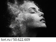 A black and white fine art photograph of a highly detailed powder dispersion effect on a woman's face. The model's eyes are closed and her face is calm, creating a sense of silence and transcendence. The powder seems to dissolve into the air, creating a dynamic cloud reminiscent of cosmic dust or a metaphor for disappearance and transformation. The photograph symbolizes beauty, fragility, purification and ephemerality, ideal for conceptual projects, cosmetic brands, skincare advertising and contemporary artistic solutions. Стоковое AI-изображение, AI-художник Анна Кривицкая / Фотобанк Лори