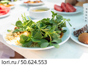Fresh green salad with herbs and grains served on a white plate in a bright outdoor setting. Стоковое фото, фотограф Наталья Семкина / Фотобанк Лори
