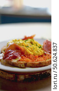 Eastern European scrambled eggs combining grated carrots and ham, nestled on toasted bread slice, positioned on white plate against neutral background. Стоковое видео, видеограф Данил Руденко / Фотобанк Лори