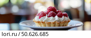 Appetizing raspberry tart and mint. Raspberry danish cake on plate on table and coffee. Tartlets raspberry fruit with vanilla custard, whipped cream served in a cafe. Blurred bokeh interior background. Стоковое AI-изображение, AI-художник Марина Демидюк / Фотобанк Лори