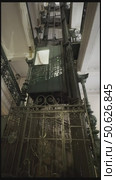 A video of a vintage elevator descending inside the stairwell of an old-world apartment building, its ornate iron gate clinking softly as it passes each floor.  Perfect for period films, historical documentaries, or luxury real estate ads, this footage captures the timeless charm of early 20th-century engineering. Ideal for evoking mystery, elegance, or retro nostalgia. Стоковое видео, видеограф Виктор Ветошкин / Фотобанк Лори