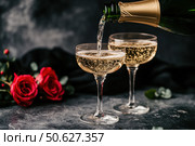 Champagne and red pink roses on a black concrete background. Copy space for text. Valentines drinks for for a pair of lovers. Bartender pours prosecco sparkling wine into glasses. Romance. Wedding Day. Стоковое AI-изображение, AI-художник Марина Демидюк / Фотобанк Лори