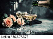 Champagne and red pink roses on a black concrete background. Copy space for text. Valentines drinks for for a pair of lovers. Bartender pours prosecco sparkling wine into glasses. Romance. Wedding Day. Стоковое AI-изображение, AI-художник Марина Демидюк / Фотобанк Лори