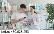 Man scans QR code on box medicated ointment or gel label. Female pharmacist offers to choose the right gel. Стоковое видео, видеограф Яков Филимонов / Фотобанк Лори